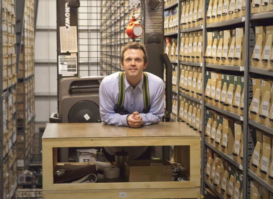 Annex manager, CJ Keough, attaches a safety harness when using the order picker to retrieve materials from the Annex shelves. 