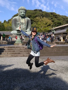 Jessica jumping in front of the Great Buddha of Kamakura.